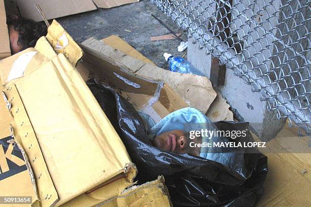 Un joven descansa cobijado con cartones y bolsas de plastico el 19 de mayo de 2004 en una acera de San Jose. La cantidad de indigentes en Costa Rica...