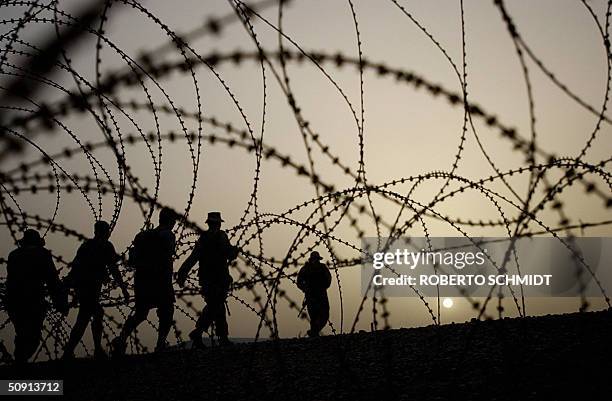 Group of US Army soldiers from the 1st Cavalry Division walks past concertina wire in the late afternoon at camp Black Jack near Baghdad 31 May 2004....