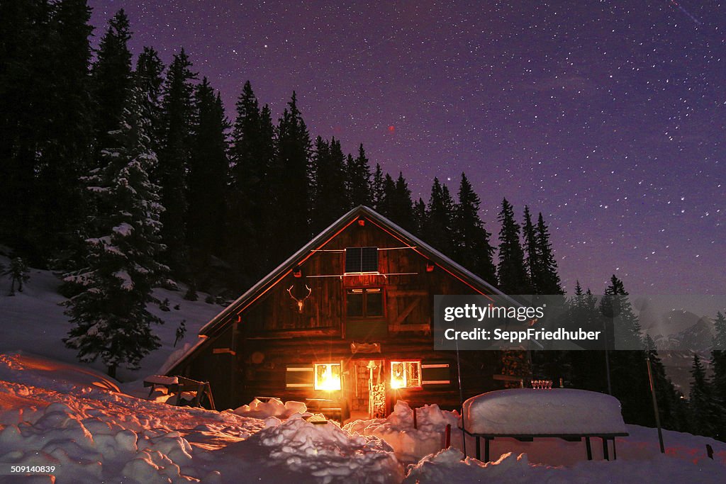 Lightened mountain hut in the austrian alps with milky way