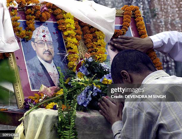 Nepalese man bows his head in prayer at an altar adorned with garlanded photographs of the late King Birendra and Queen Aishwarya at Patan,...