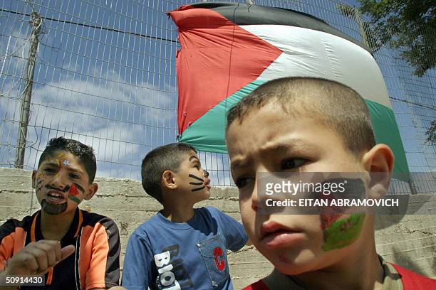 Palestinian boys, standing under a huge national flag, celebrate 01 June 2004 the International Children Day at a youths activities center in the...