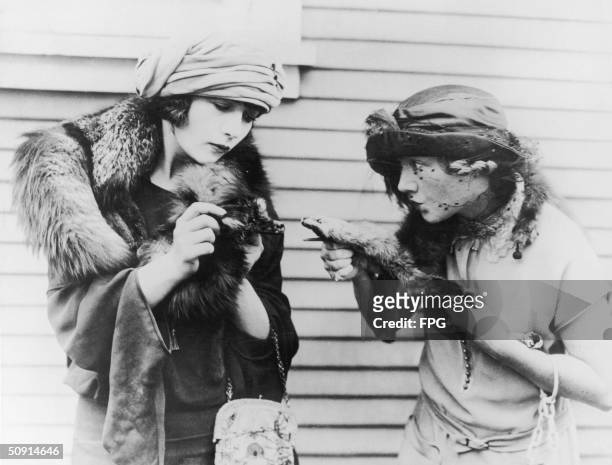 Two smartly-dressed women stage a mock fight with their mink stoles, circa 1925.