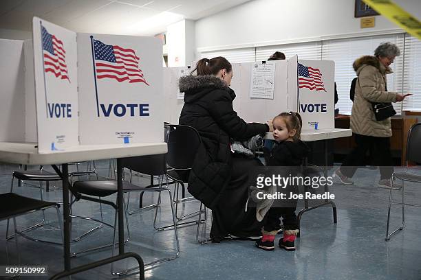 Primary day voter Amanda Binette fills out her ballot as her daughter, Emmaline Binette, 2 years old, stands next to her at a polling station setup...