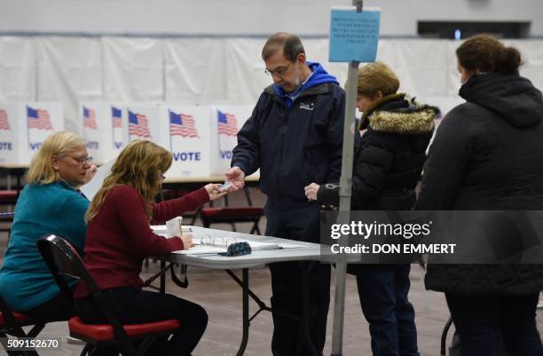 Voter's show their identification to polling station workers as they prepare to cast ballots at Belmont High School February 9, 2016 in Belmont New...