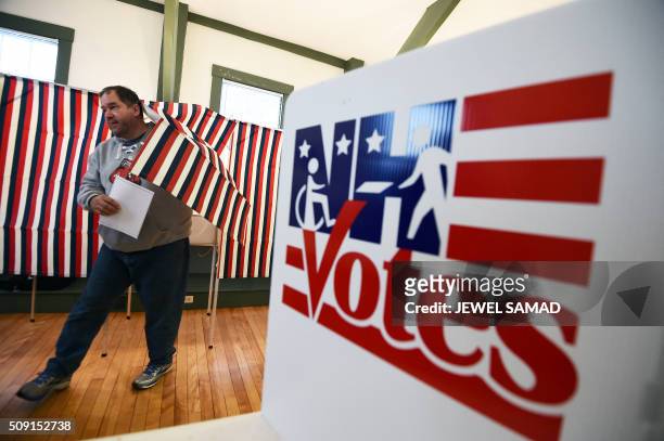 Man walks out of a booth with his ballot for the first US presidential primary at the town hall in Canterbury, New Hampshire, on February 9, 2016....