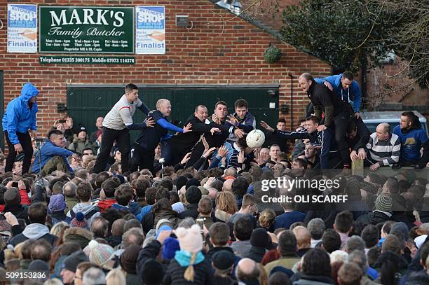 Competitors from the opposing teams, the Up'ards and the Down'ards, reach for the ball during the annual Royal Shrovetide Football Match in...