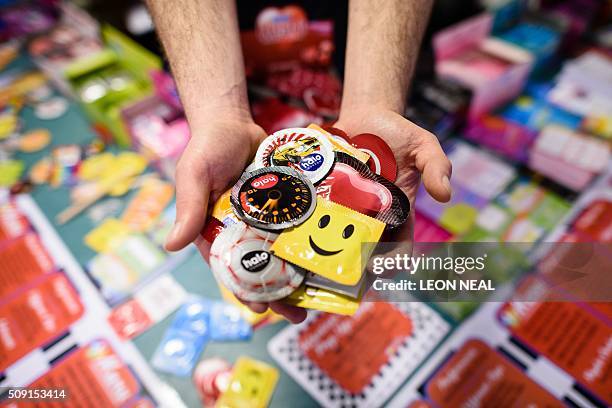 Man poses holding a selection of unusual condoms are displayed at the Valentine's Condom pop-up shop in east London on February 9, 2016. "Come...