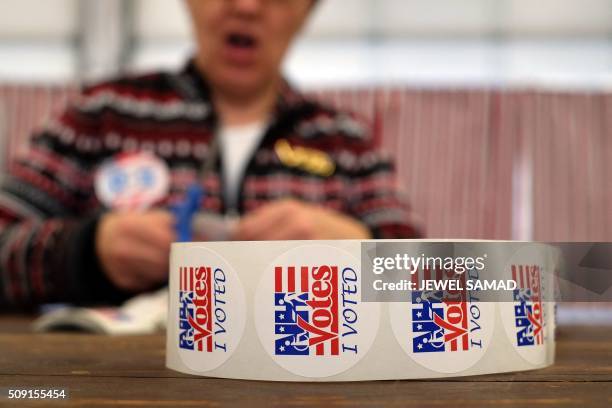 An electoral official prepares "I Voted" stickers as local residents vote for the first US presidential primary at a fire station in Loudon, New...