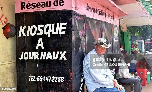 Men sit in front of a closed newspaper stand in Conakry on February 9 on a "press-free day" in honour of a journalist who was shot dead last week....