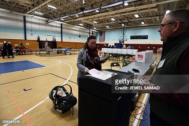 Woman with a baby casts her ballot for the first US presidential primary at a school gym in Concord, New Hampshire, on February 9, 2016. New...