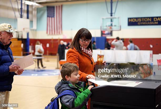 Woman with a child casts her ballot for the first US presidential primary at a school gym in Concord, New Hampshire, on February 9, 2016. New...