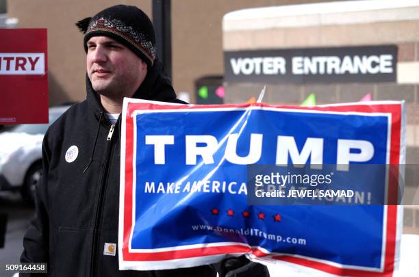 Supporter of US Republican presidential candidate Donald Trump displays a campaign poster as residents vote for the first US presidential primary at...