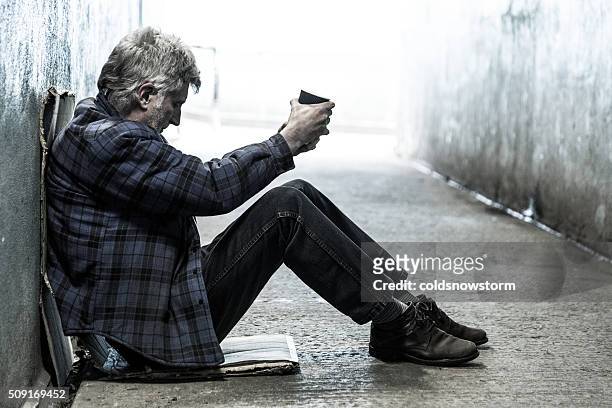 homeless senior adult man sitting and begging in subway tunnel - beggar stock pictures, royalty-free photos & images