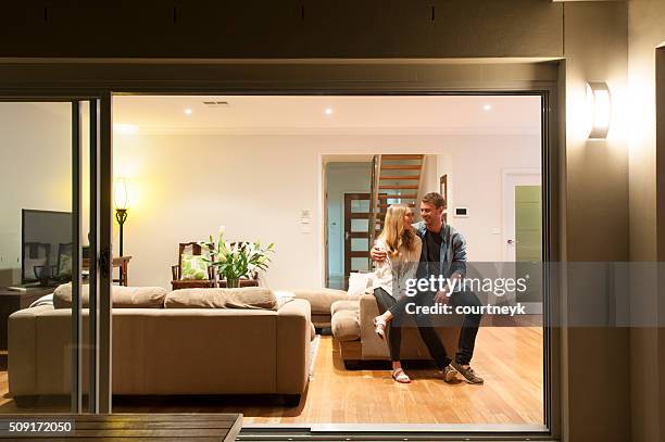 couple relaxing in their home at night. - new sofa stock pictures, royalty-free photos & images