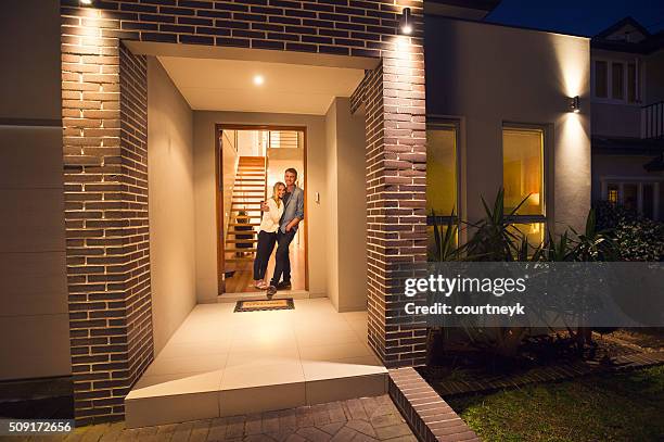 couple standing in front of their new home. - brick house door stock pictures, royalty-free photos & images