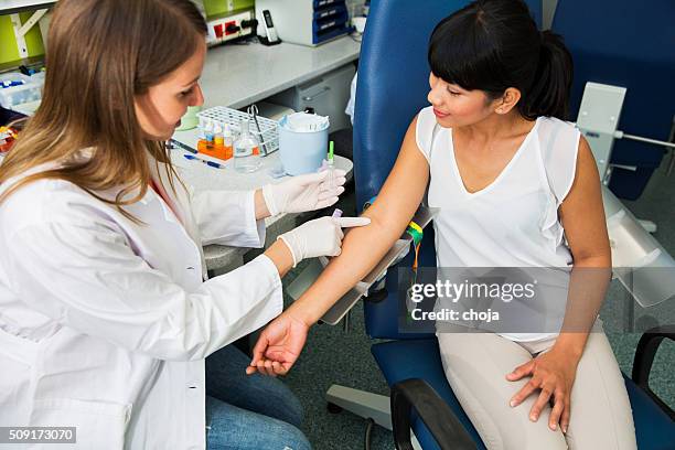 drawing blood...young doctor prepairing for blood capture - iv going into an arm stock pictures, royalty-free photos & images