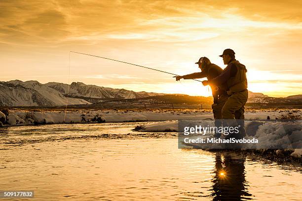 guida per la pesca che indica una trota al tramonto - fly fishing foto e immagini stock