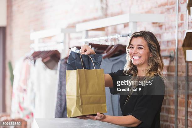 young woman with shopping bag in clothing store - shop stockfoto's en -beelden