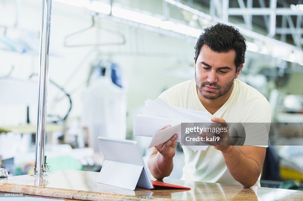 Hispanic small business owner, dry cleaner paying bills