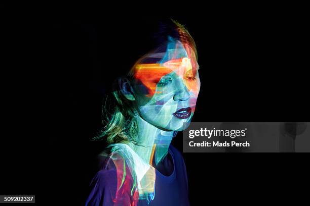 young woman with multicolored light in her face - emotion imagens e fotografias de stock