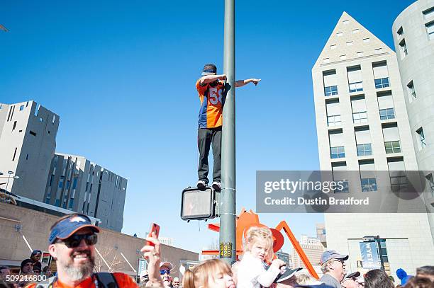 Denver Broncos fan performs a "dab" wearing a Von Miller jersey as he watches from a light pole as Broncos players and personnel take part in a...