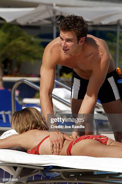 Michael Sheehan, who works as a Tanning Butler at The Ritz-Carlton South Beach, applies sun tan lotion to the body of Leah Danna June 3, 2004 in...