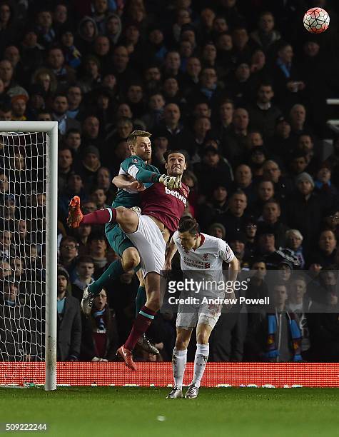 Simon Mignolet of Liverpool punches the ball away from Andy Carroll of West Ham United during The Emirates FA Cup Fourth Round Replay match between...