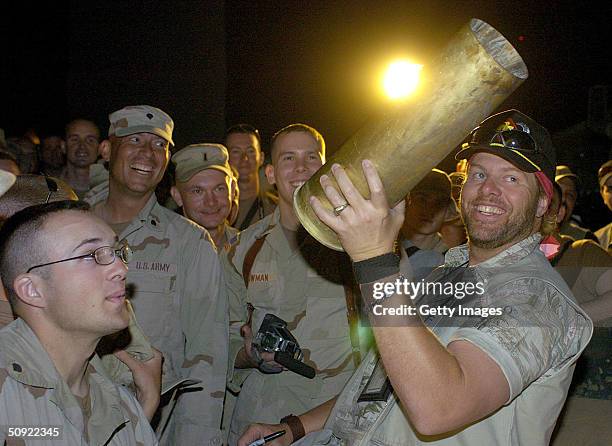 In this handout image provided by the United Service Organizations , country music star Toby Keith holds an artillery shell he is asked to autograph...