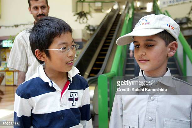 Mohamad Haytham Saleh, a 10-year-old Iraqi boy, talks to a Japanese boy at a parking area on the way to the hospital on June 4, 2004 in Ebina,...