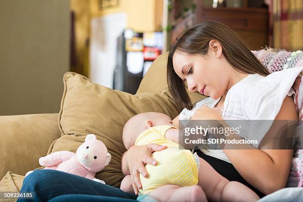 young mom breastfeeding infant daughter at home - dia bildbanksfoton och bilder