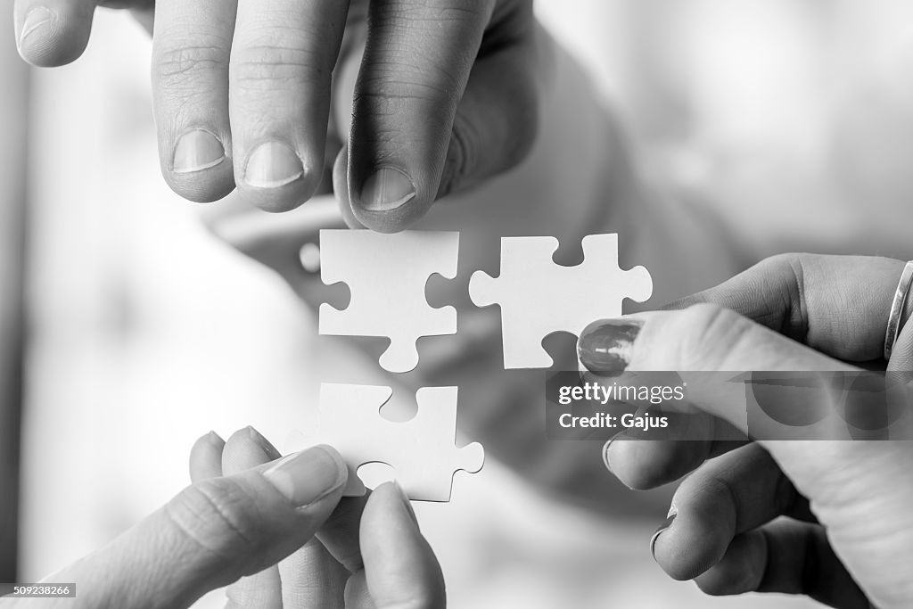 Three people holding puzzle pieces to match them