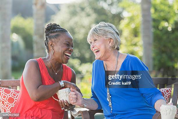 senior women enjoying cup of coffee together, talking - two women talking stockfoto's en -beelden