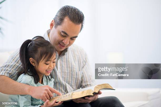 padre e hija leyendo un libro juntos - religious text fotografías e imágenes de stock