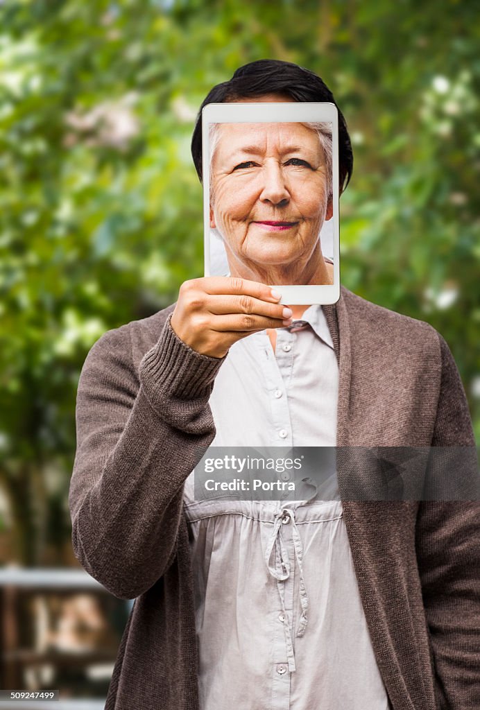 Woman showing image of old lady on digital tablet