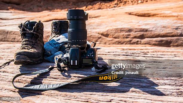 nikon camera with boots on the ground after a hike. - nikon stock pictures, royalty-free photos & images