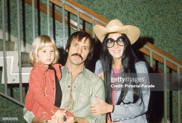 American singers and actors Sonny and Cher Bono pose with their daughter Chastity in front of a staircase, March 1, 1973.