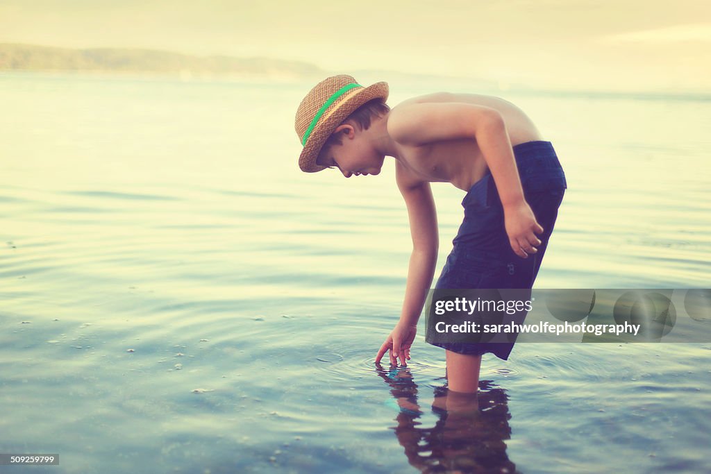 Young boy dipping his finger in water