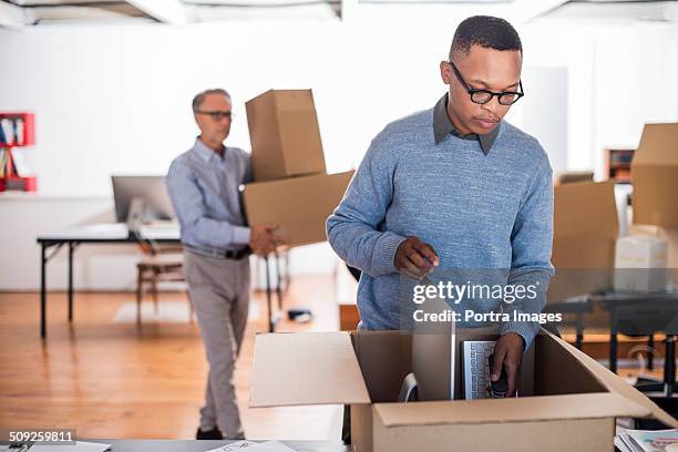 businessmen packing cardboard boxes in office - moving office stock pictures, royalty-free photos & images