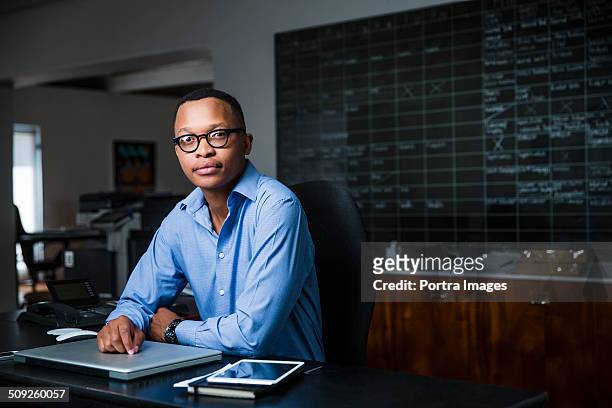 confident businessman sitting in creative office - black man looking at camera stock pictures, royalty-free photos & images