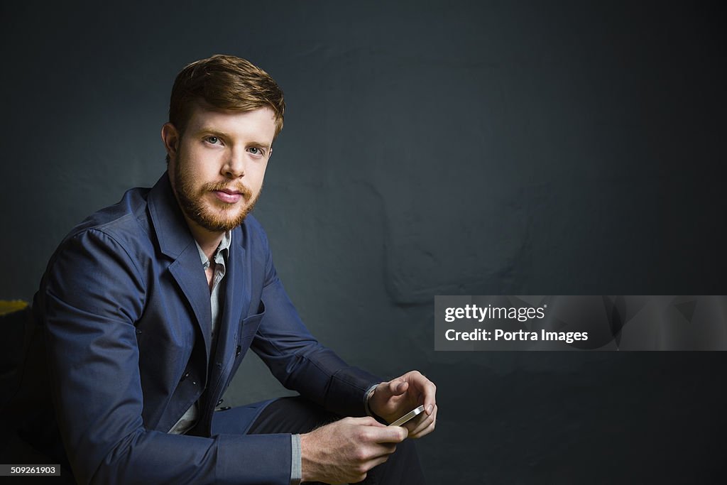 Confident businessman holding smart phone