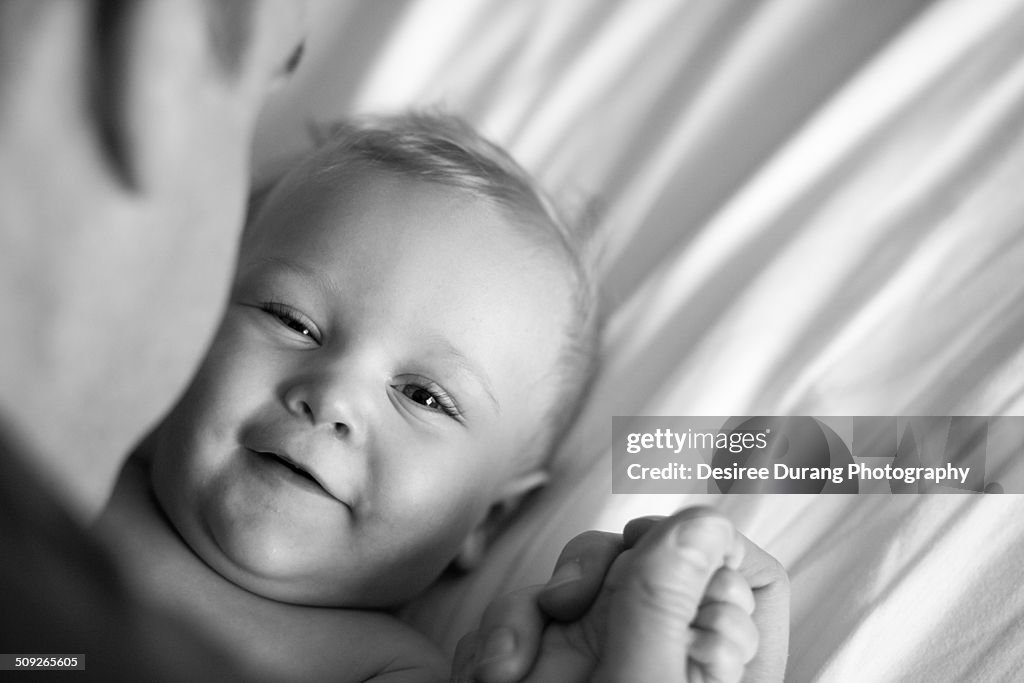 A baby laying down playing with dad