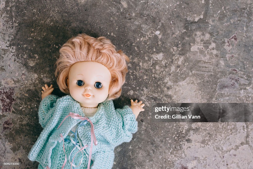 Old doll abandoned on a concrete floor