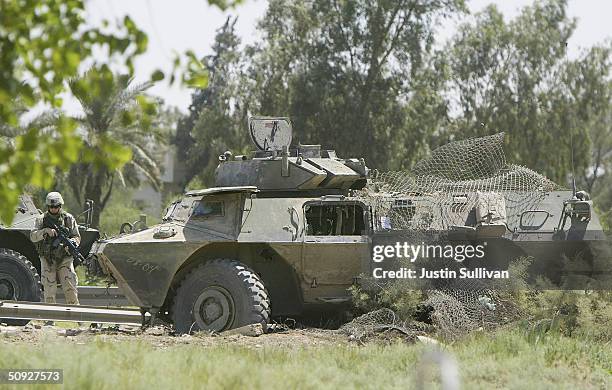Soldier stands near a Striker armored vehicle that was hit by a roadside attack June 5, 2004 in Baghdad, Iraq. One soldier was killed and three more...