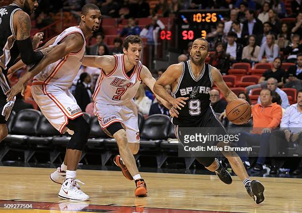 Tony Parker of the San Antonio Spurs drives past Goran Dragic and Chris Bosh of the Miami Heat during a game at American Airlines Arena on February...