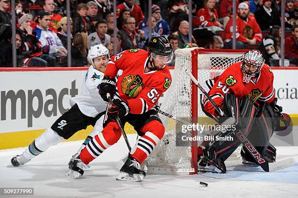 Erik Gustafsson of the Chicago Blackhawks and Joe Pavelski of the San Jose Sharks chase the puck around the net guarded by goalie Corey Crawford in...