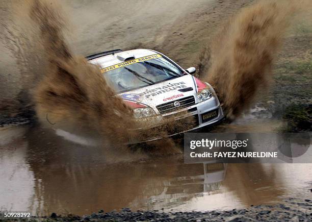 French Mathieu Biasion and co-driver Eric Domenech speed their Fiat Punto Super 1600 through a muddy pool, during the Acropolis Rally of Greece in...