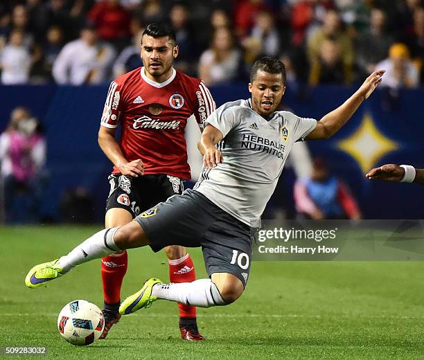 Giovani Dos Santos of Los Angeles Galaxy is tripped by Alberto Garcia of Club Tijuana during the second half at StubHub Center on February 9, 2016 in...