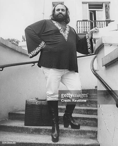 Portrait of singer Demis Roussos standing on a staircase in London, July 9th 1976.