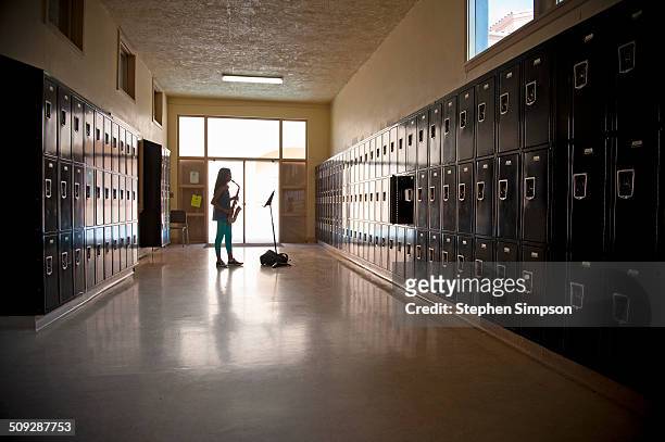teen girl practicing saxophone in empty hallway - school building silhouette stock pictures, royalty-free photos & images