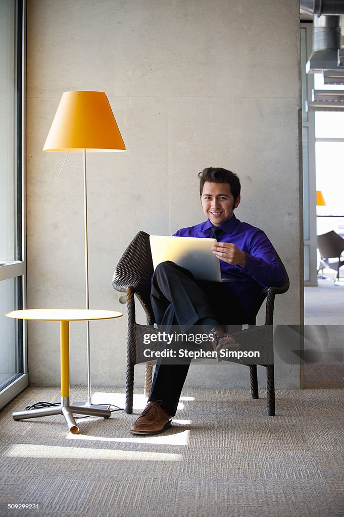 Young businessman in waiting room with laptop